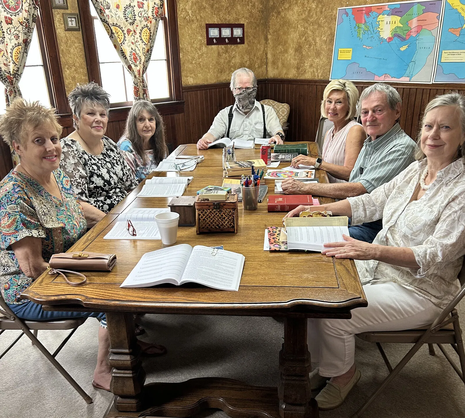 The Bible study group seated around a long table with open study books and a map of the Bible lands.