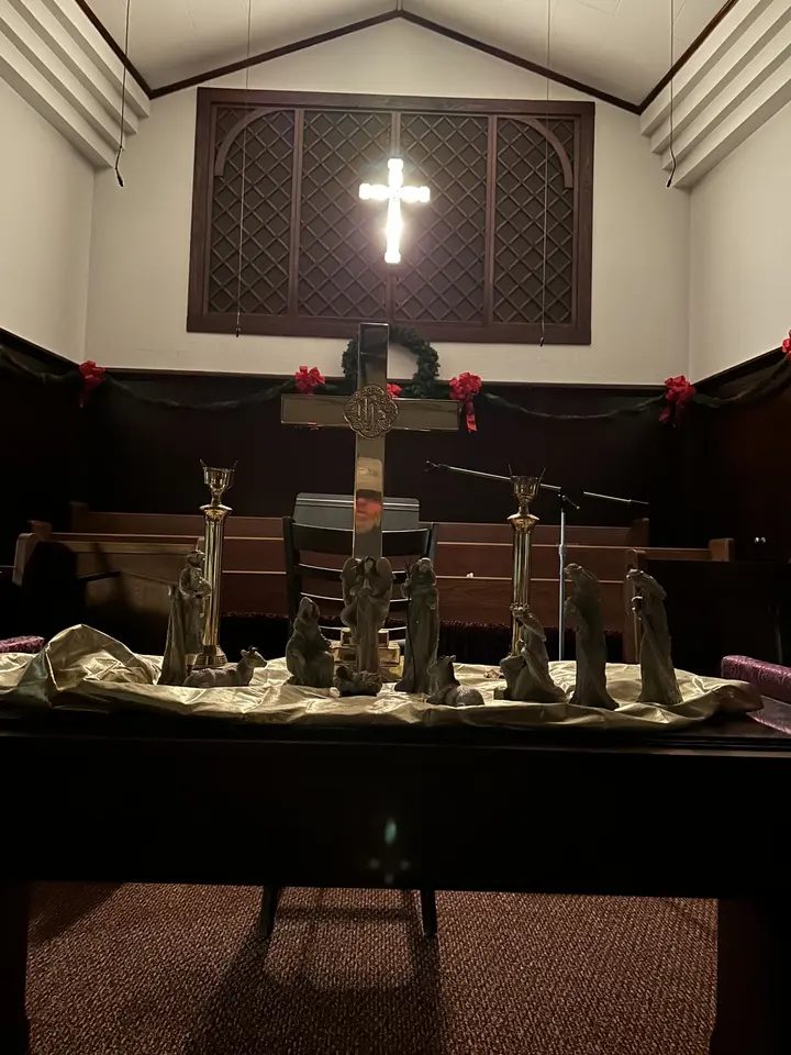 The chancel with the carved wooden cross above the altar, brass candlesticks, and a draped gold paramant.