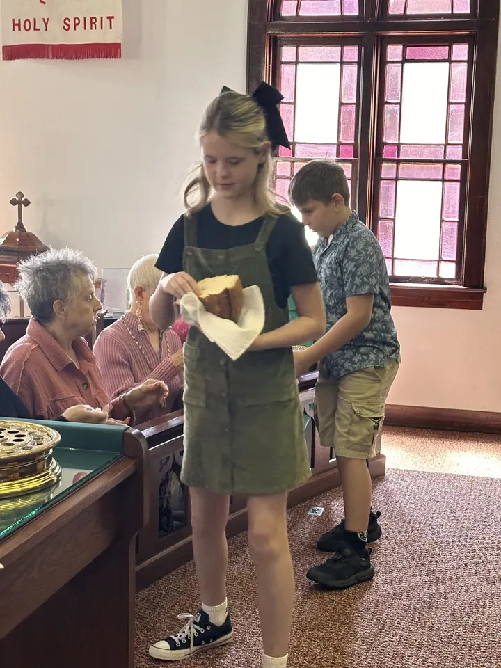 A girl receiving a wrapped Christmas gift from a longtime member at the front of the sanctuary.