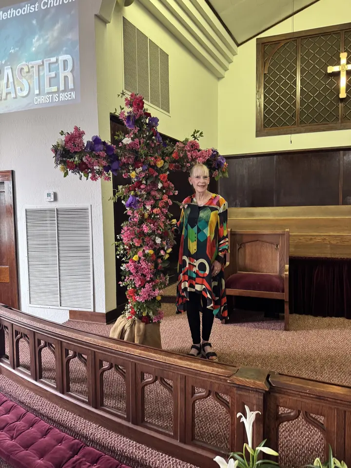 The sanctuary on Easter, banked with white lilies and red flowers beneath an "Easter" banner.