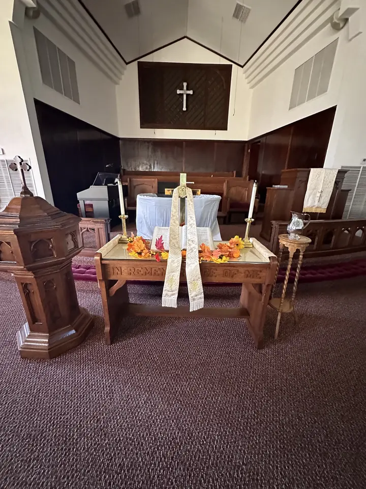 The altar arranged for the fall harvest with pumpkins, gourds, and an open Bible before the cross.