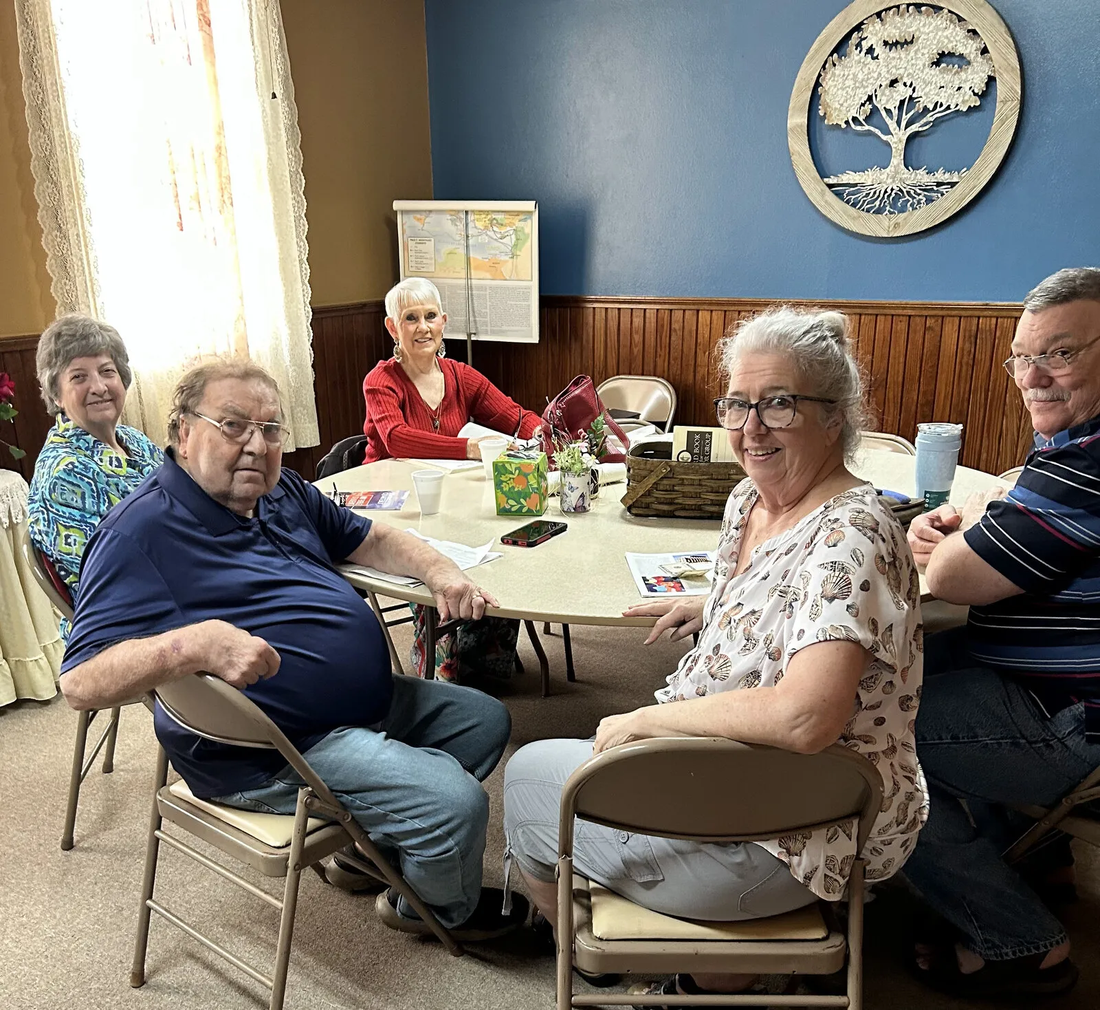 Members of the church family gathered around a table in the fellowship hall.