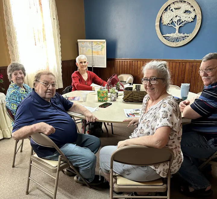 Members of the church family gathered around a table in the fellowship hall.