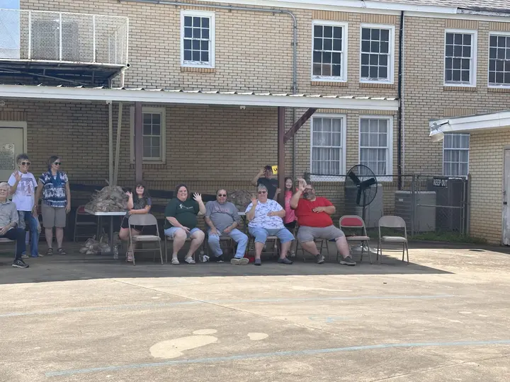 Neighbors and volunteers seated outside the fellowship hall on food pantry day.