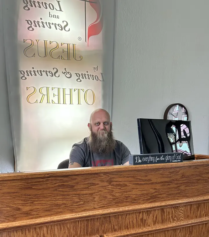 A church member seated at the front of the sanctuary beneath the congregation’s motto banner.