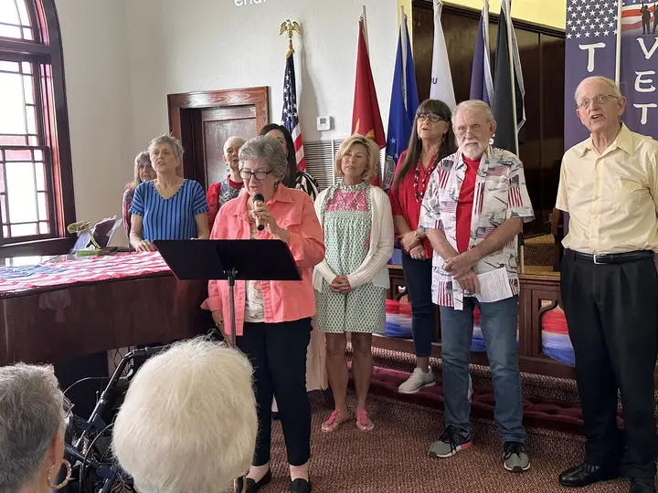 Members of the church singing together with U.S. and military service flags behind them on Memorial Day.