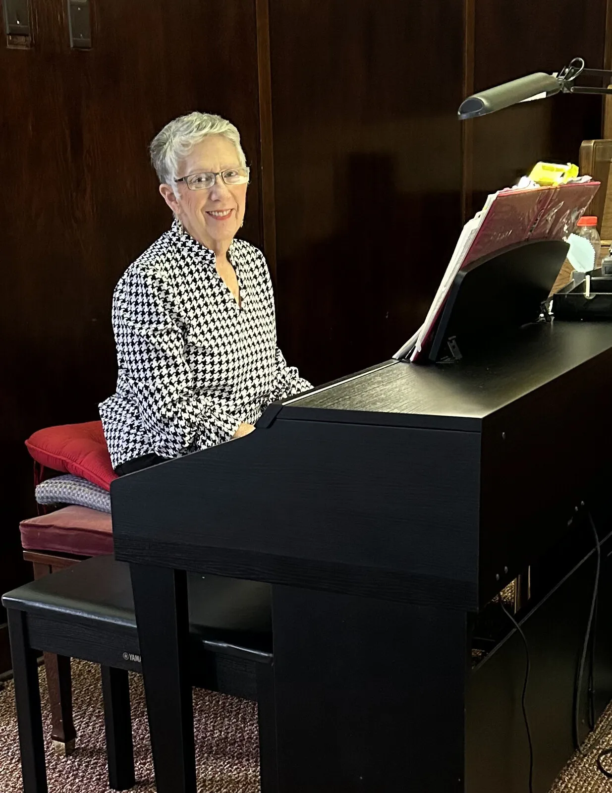 The church pianist seated at the piano with open sheet music during worship.
